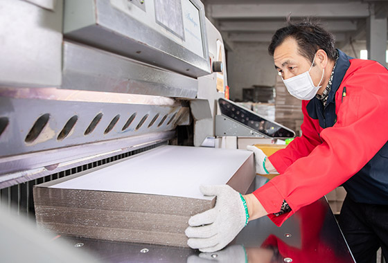 a-worker-cutting-the-cardboard-by-using-the-machine